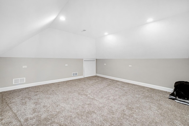 additional living space with baseboards, visible vents, vaulted ceiling, and carpet flooring