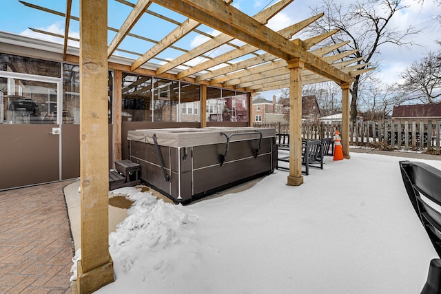 snow covered patio featuring fence, a hot tub, and a pergola