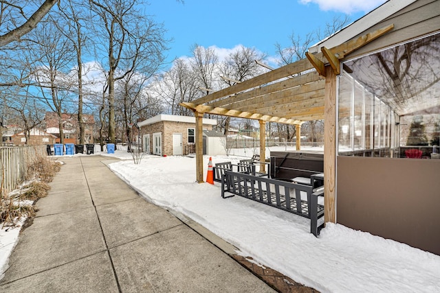 snow covered patio featuring a hot tub, an outdoor structure, fence, and a pergola