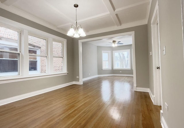 empty room with an inviting chandelier, coffered ceiling, dark hardwood / wood-style floors, and beamed ceiling