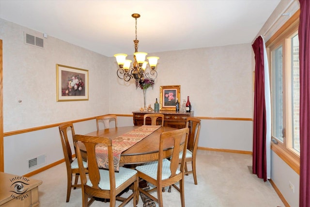 dining area featuring a healthy amount of sunlight, light carpet, and an inviting chandelier