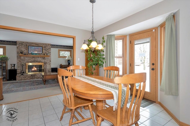 dining area featuring light tile patterned floors, a notable chandelier, and a fireplace