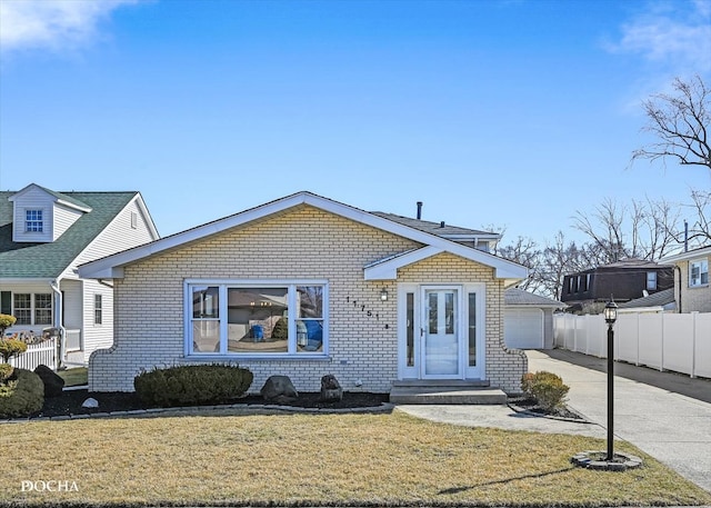 bungalow-style house with brick siding, a front yard, and fence