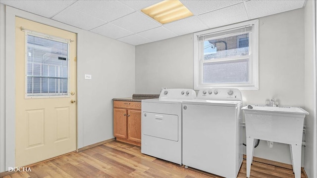 washroom with cabinet space, independent washer and dryer, light wood finished floors, and baseboards