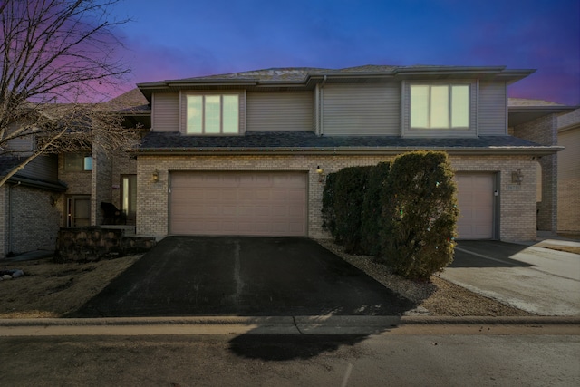 view of front facade with driveway, brick siding, and an attached garage