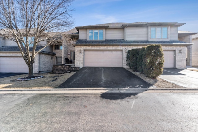 view of front of home featuring driveway, a garage, and brick siding