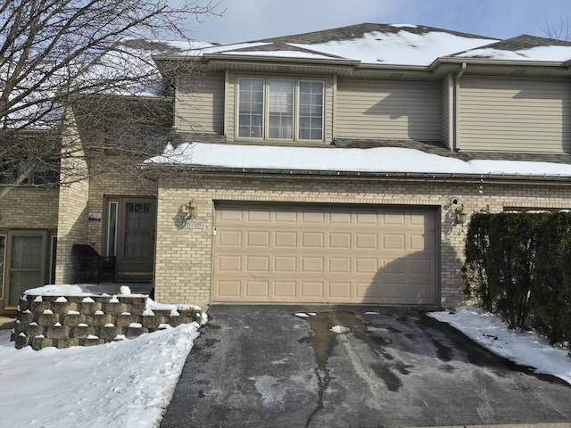 exterior space featuring an attached garage, driveway, and brick siding