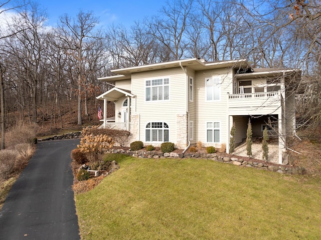 view of side of property with a balcony and a yard