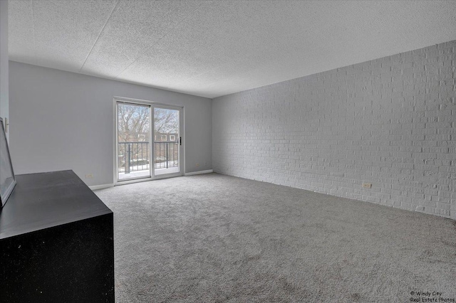 unfurnished living room featuring brick wall, carpet, and a textured ceiling