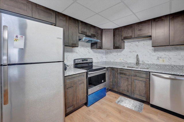 kitchen with stainless steel appliances, light stone countertops, sink, and dark brown cabinetry