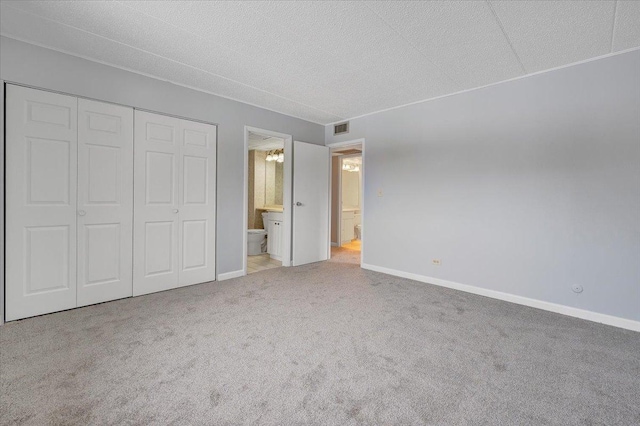 unfurnished bedroom with light carpet, ensuite bath, and a closet