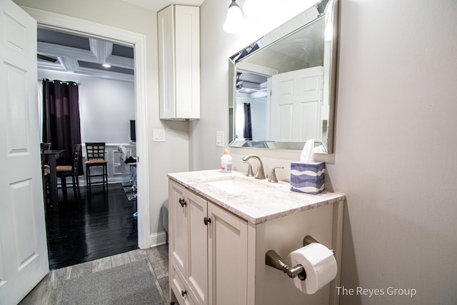 bathroom with vanity, wood finished floors, baseboards, coffered ceiling, and beam ceiling