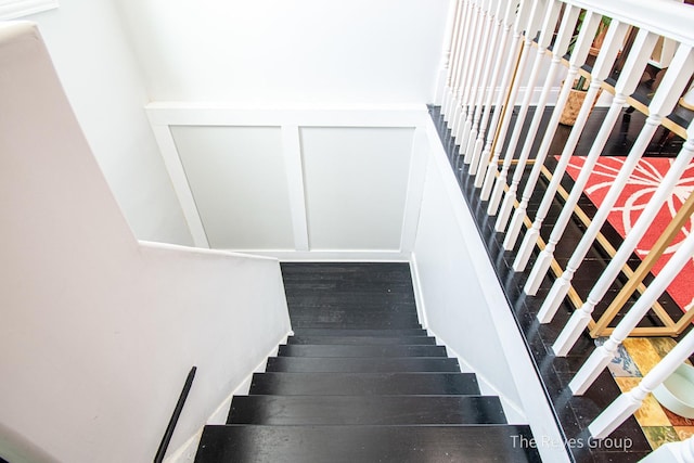 stairs with wood finished floors and a decorative wall