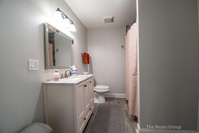 bathroom featuring baseboards, toilet, wood finished floors, and vanity