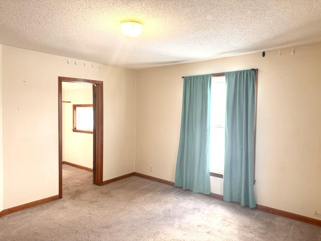 empty room featuring light colored carpet, a healthy amount of sunlight, and a textured ceiling