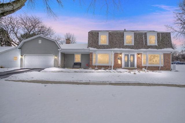 view of front of property featuring a garage, brick siding, and roof with shingles