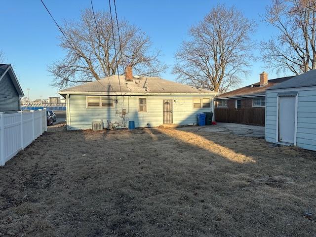 rear view of house featuring a chimney and fence