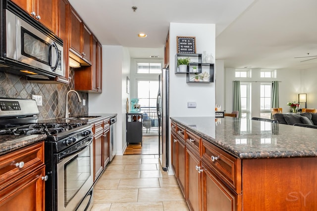 kitchen featuring dark stone countertops, appliances with stainless steel finishes, sink, and plenty of natural light