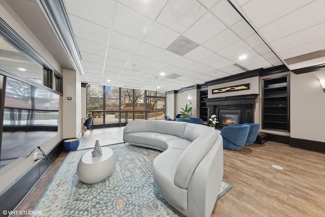 living room featuring a drop ceiling, wood-type flooring, and a wall of windows