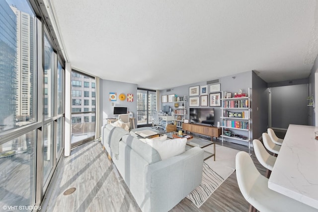 living room featuring light hardwood / wood-style flooring, expansive windows, and a textured ceiling