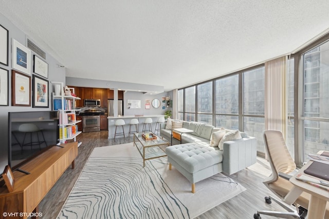 living room featuring light hardwood / wood-style floors, a textured ceiling, and expansive windows