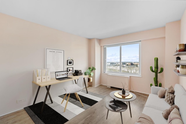 home office with light wood finished floors, radiator heating unit, and baseboards