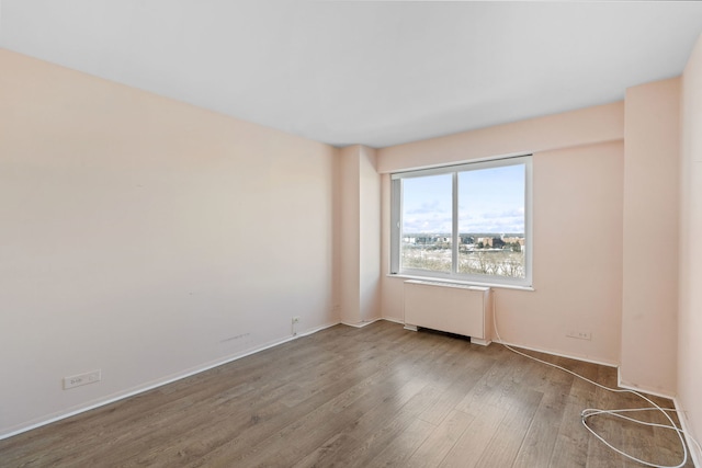 empty room with radiator and wood finished floors