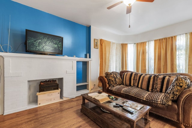 living area with ceiling fan, a fireplace, and wood finished floors