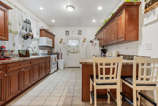 kitchen with white appliances, light tile patterned flooring, a sink, and recessed lighting