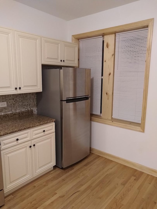 2921 N Kedzie Ave, Chicago, IL 60618 - kitchen featuring baseboards, dark stone counters, decorative backsplash, light wood-style flooring, and freestanding refrigerator