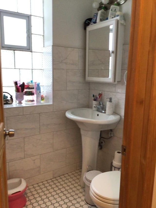 half bath featuring toilet and tile walls