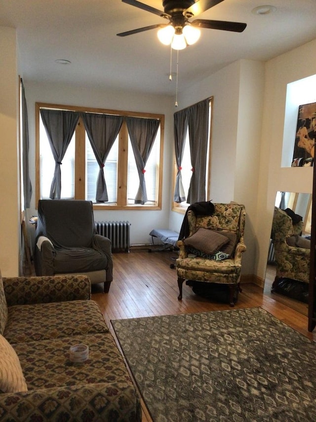 interior space with radiator heating unit, wood finished floors, a ceiling fan, and baseboards