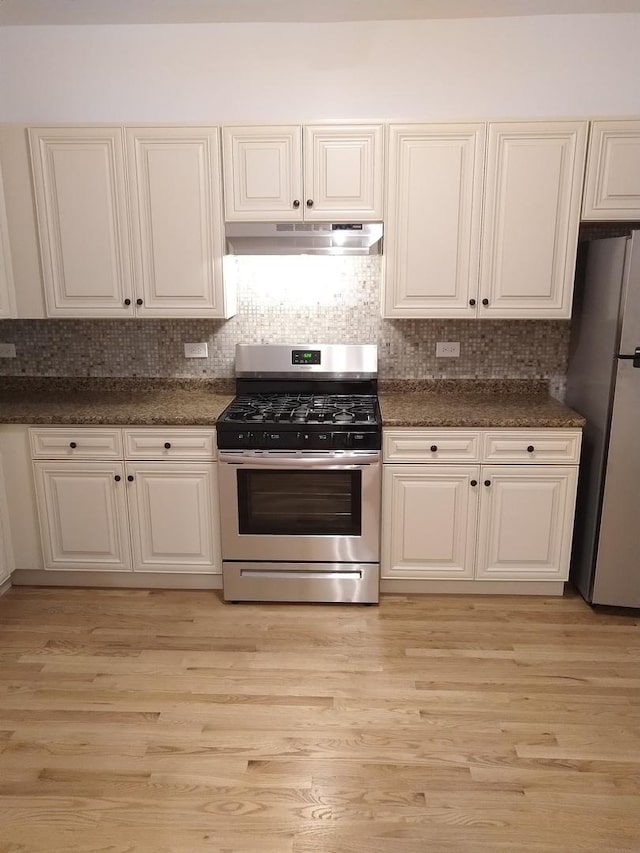2921 N Kedzie Ave, Chicago, IL 60618 - kitchen with under cabinet range hood, dark stone counters, stainless steel appliances, and light wood finished floors