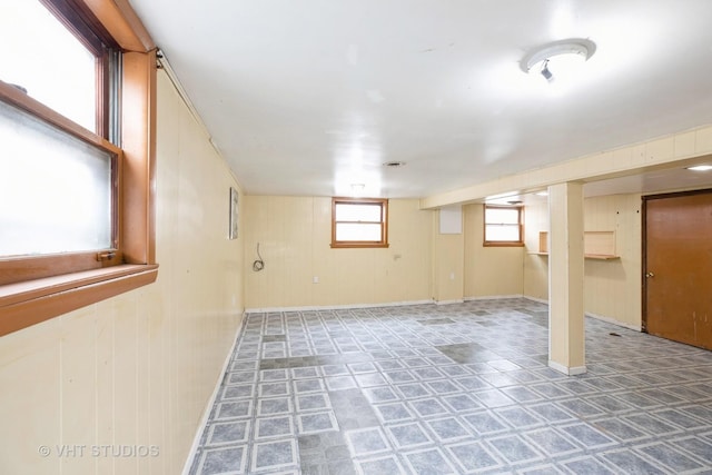 below grade area featuring tile patterned floors and wood walls