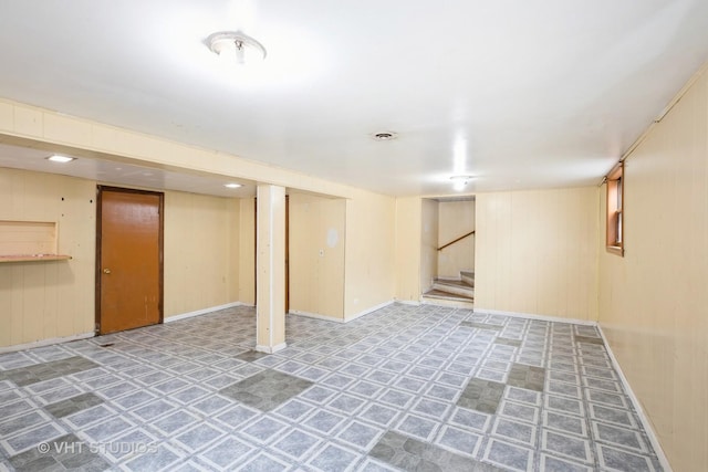 finished basement with wooden walls, baseboards, and stairs