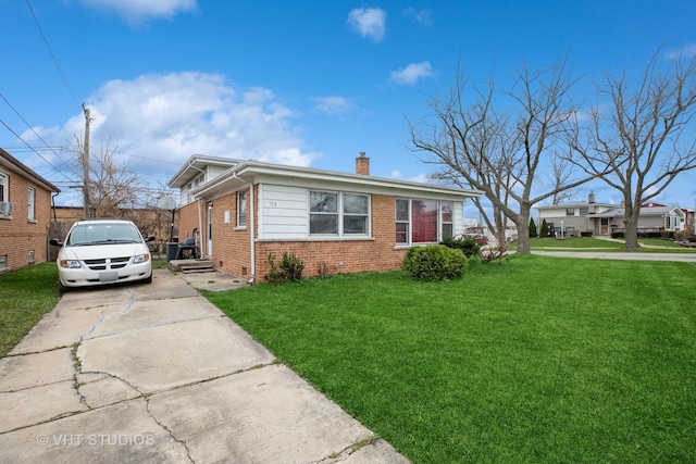bungalow-style home featuring a chimney, driveway, a front yard, and brick siding
