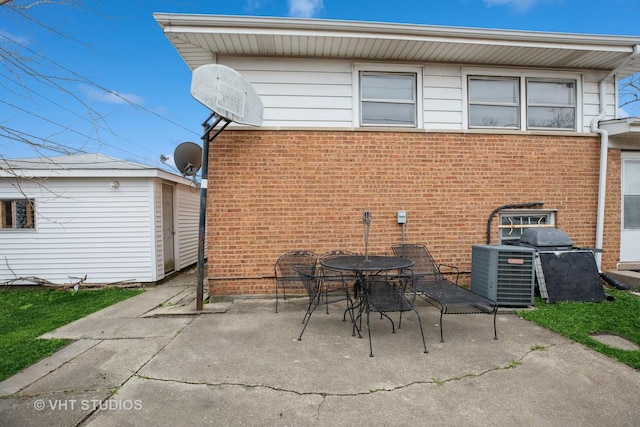 rear view of property with an outbuilding, cooling unit, a patio area, brick siding, and outdoor dining space