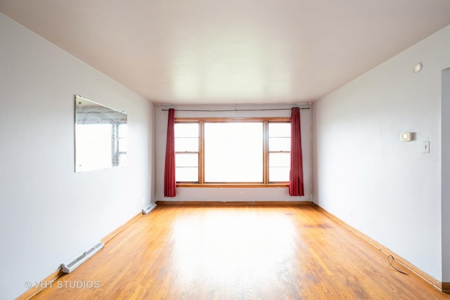 spare room featuring light wood-style floors, baseboards, visible vents, and a wealth of natural light