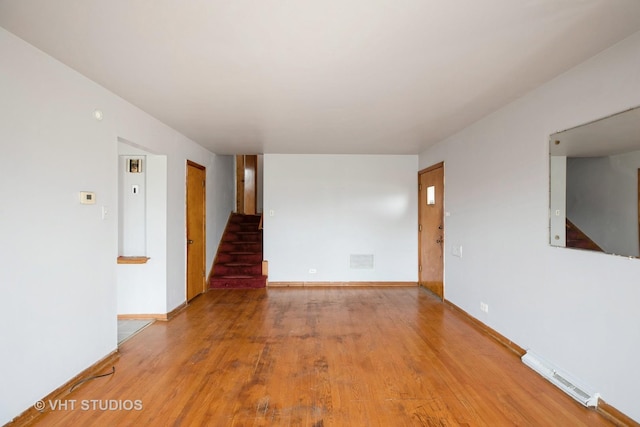 unfurnished room with wood finished floors, baseboards, visible vents, and stairs