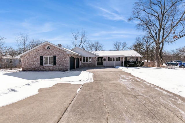 ranch-style house featuring an attached garage, a chimney, concrete driveway, and brick siding