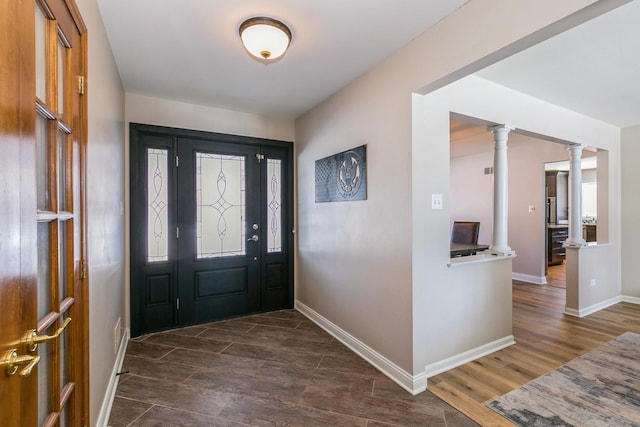 foyer entrance featuring dark wood-style flooring, decorative columns, and baseboards