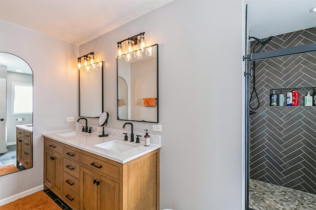 bathroom with tiled shower, a sink, and double vanity