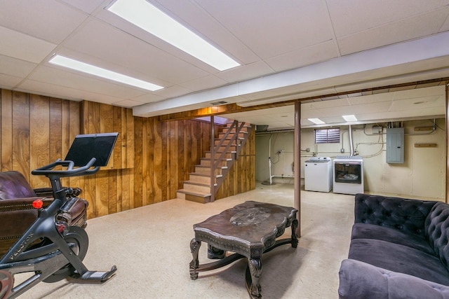 interior space with wood walls, electric panel, washer and clothes dryer, and a drop ceiling