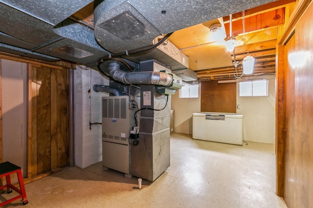 basement with fridge, heating unit, and tile patterned floors