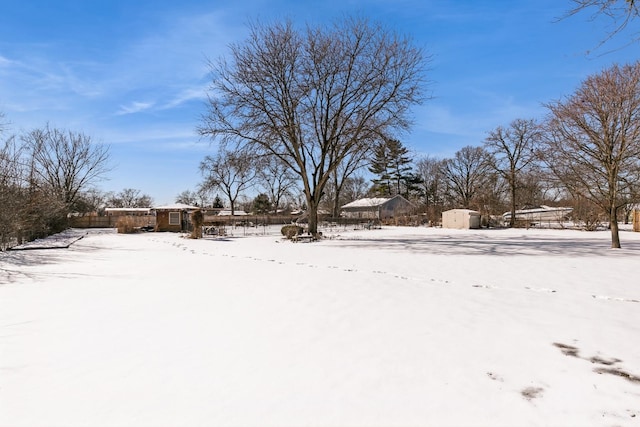 yard covered in snow with a storage shed and an outdoor structure