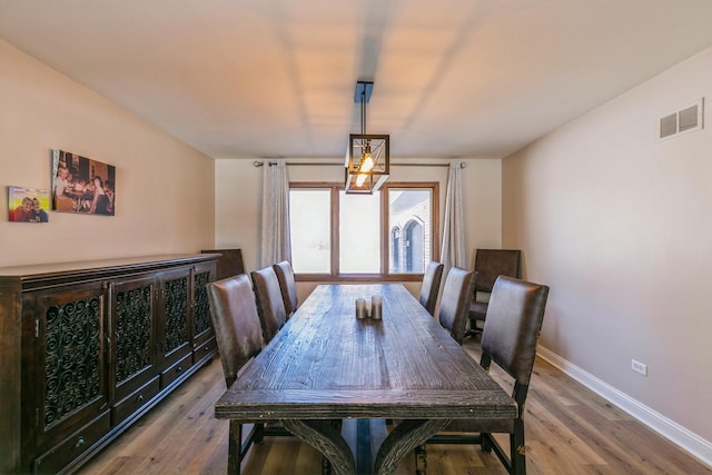 dining space with wood finished floors, visible vents, and baseboards