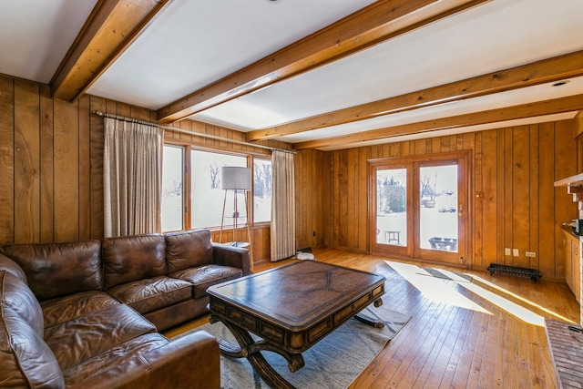 living room featuring a wealth of natural light, beam ceiling, wood finished floors, and wood walls