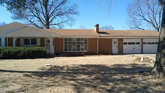 single story home featuring driveway, a shingled roof, a chimney, and an attached garage