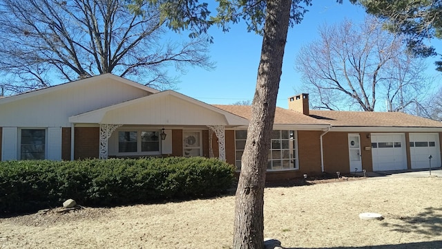 ranch-style house featuring an attached garage, driveway, a chimney, and roof with shingles