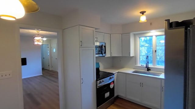 kitchen with dark wood-style floors, light countertops, appliances with stainless steel finishes, white cabinets, and a sink